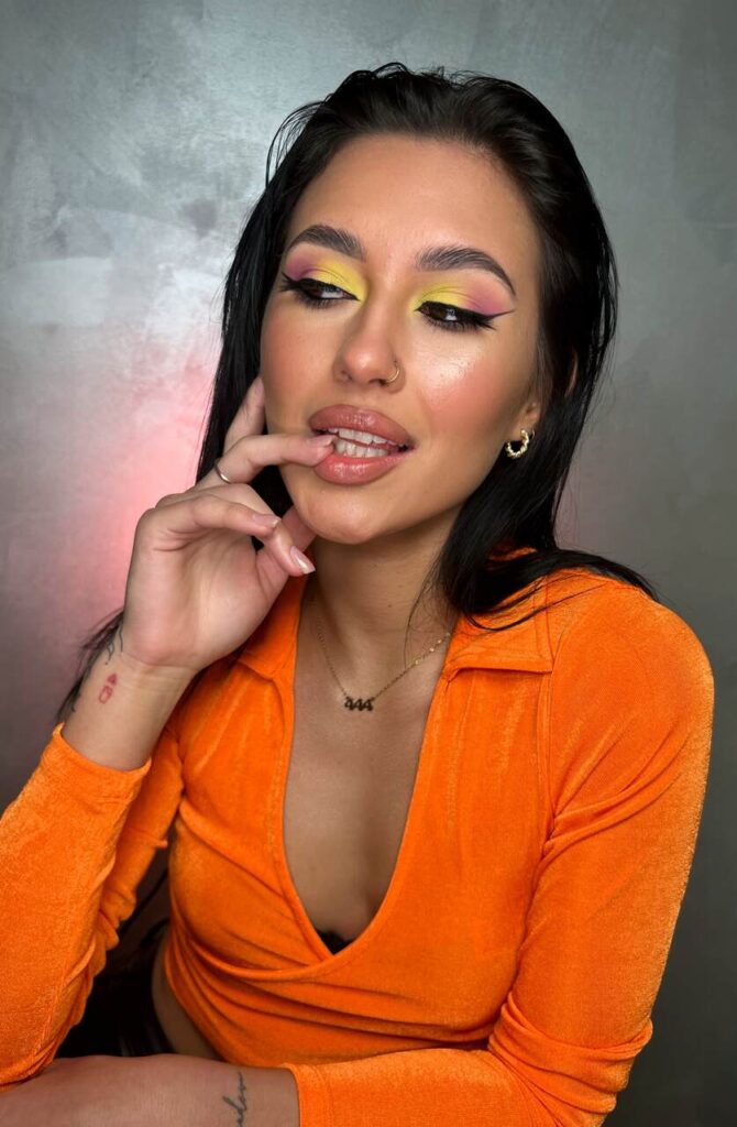 Modelka w kolorowym makijażu i pomarańczowej bluzce